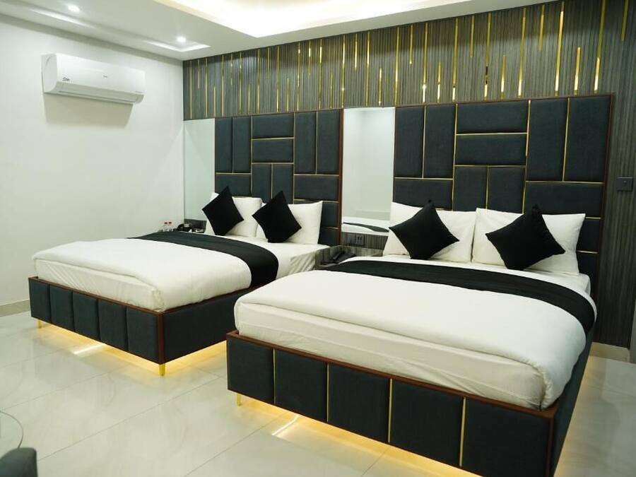 A modern bedroom with two beds, a mirrored headboard, and a built-in air conditioning unit.