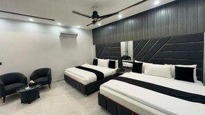 Una habitación de hotel moderna con dos camas, un ventilador de techo y un pequeño rincón de descanso.