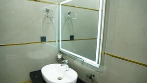 Un baño con un lavamanos blanco, un espejo y un perchero para toallas.