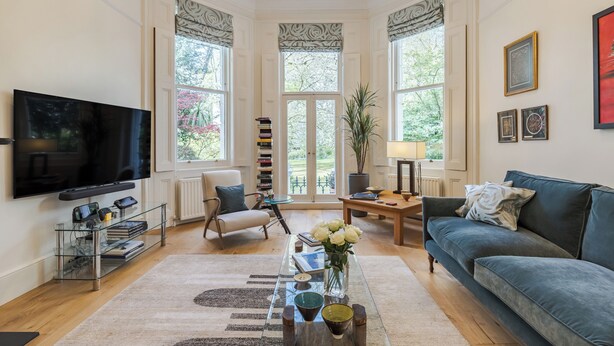 A living room with a TV, sofa, coffee table, and a view of greenery outside. - South Kensington Garden Escape, by Veeve (London)