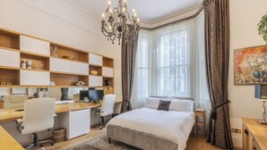 A bedroom with a bed, desk, chair, and a chandelier. - South Kensington Garden Escape, by Veeve (London)