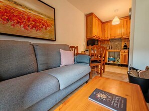Ein Wohnzimmer mit grauem Sofa, einem Holztisch und einem Bild an der Wand.