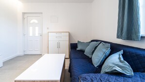 Een kleine, moderne kamer met een bed, een witte tafel en een kledingkast.