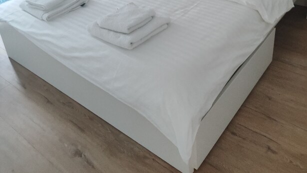 Een opgemaakt bed met witte lakens en handdoeken.