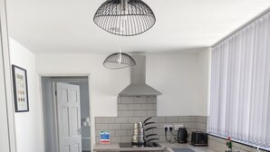 A modern kitchen with a built-in oven, a dishwasher, and a kettle on the countertop. - Stylish Modern 2 Bedroom House close to City, Siemens, BP (Kingston upon Hull)