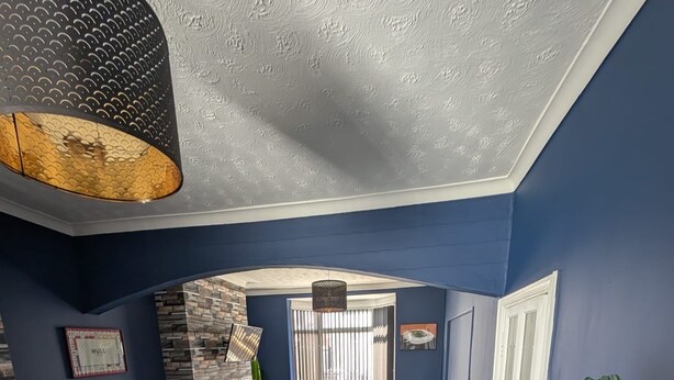 A modern living room with a blue wall, a stone accent wall, a dark grey sofa, a wooden coffee table, and a hanging light fixture. - Stylish Modern 2 Bedroom House close to City, Siemens, BP (Kingston upon Hull)