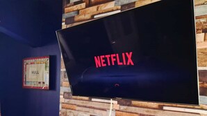 A television screen with the Netflix logo, mounted on a wall with a wooden panel design. - Stylish Modern 2 Bedroom House close to City, Siemens, BP (Kingston upon Hull)