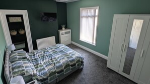 A bedroom with a bed, a desk, a wardrobe, a radiator, a window with blinds, and a ceiling light. - Stylish Modern 2 Bedroom House close to City, Siemens, BP (Kingston upon Hull)