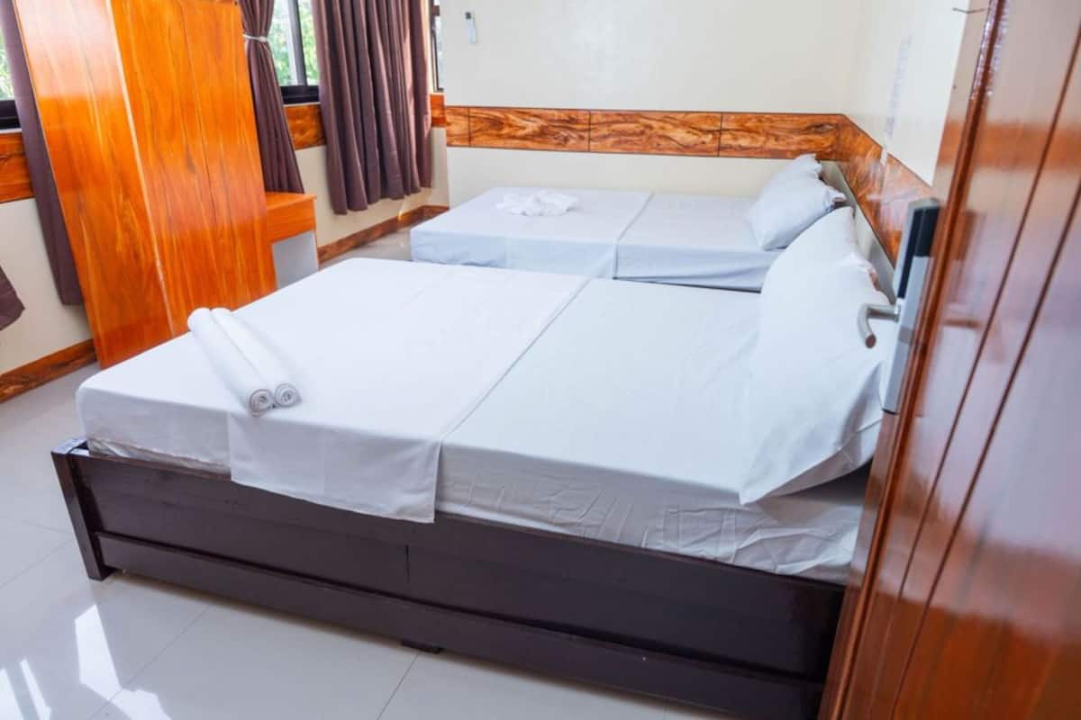 A hotel room with two beds, wooden headboards, a small table, and a mirror.