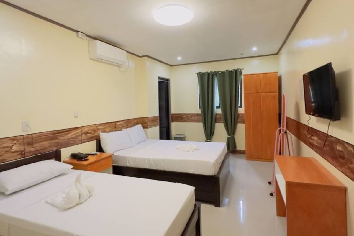A hotel room with two beds, a desk, a TV, and a wardrobe.