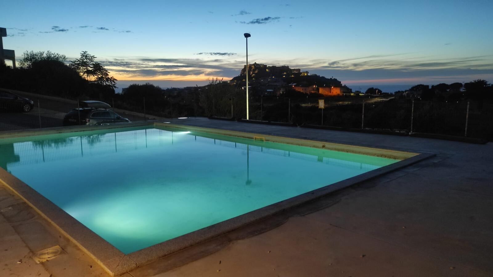 Une piscine rectangulaire dont les bords sont recouverts de carreaux, entourée d’une terrasse en béton.