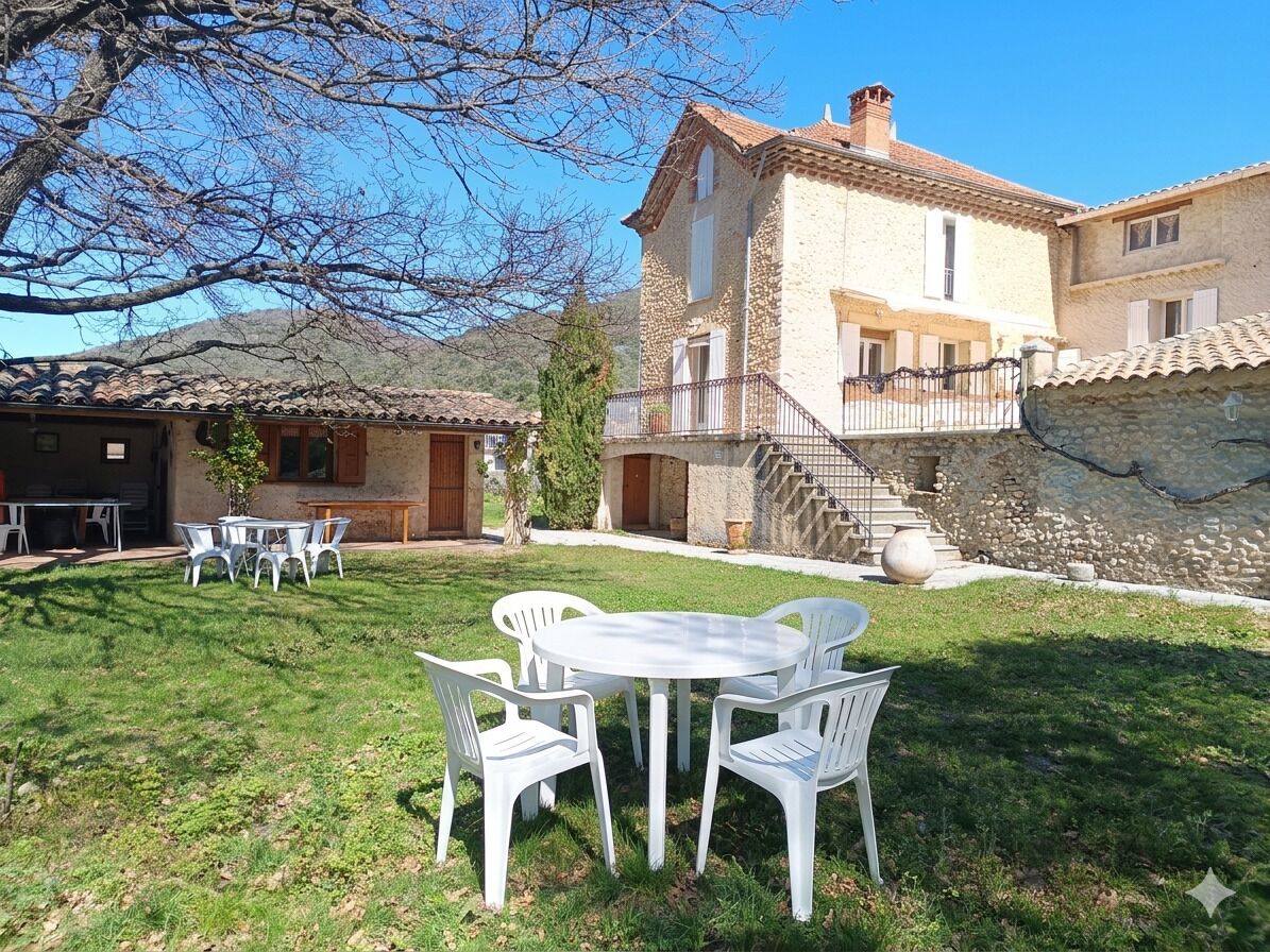 A stone building with a balcony, a grassy yard, and outdoor seating.