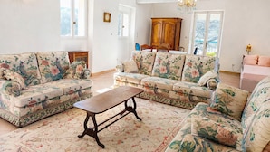 A living room with floral-patterned sofas, a wooden coffee table, and a chandelier. - Mas provençal - Large garden & lavender view - 7 people (Malijai)