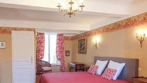 A bedroom with a bed, a chandelier, a chair, a small table, and a door. - Mas provençal - Large garden & lavender view - 7 people (Malijai)
