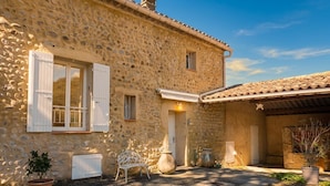 A stone building with a door, windows, and a small garden area with a bench and potted plants. - Mas provençal - Large garden & lavender view - 7 people (Malijai)