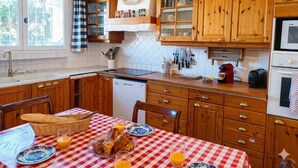 A kitchen with wooden cabinets, a red and white checkered tablecloth, and a breakfast setup. - Mas provençal - Large garden & lavender view - 7 people (Malijai)