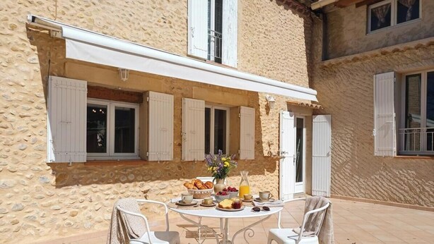 A stone building with a covered outdoor dining area, white shutters, and a table set with food and drinks. - Mas provençal - Large garden & lavender view - 7 people (Malijai)