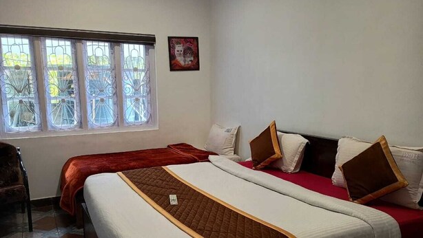 Une chambre d’hôtel avec deux lits, une fenêtre donnant sur un beau paysage et un tableau encadré au mur.