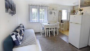 A compact kitchen with a dining area, a refrigerator, and a window with curtains. - Cozy Apartment With Garden (Umag)