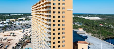 A high-rise hotel with multiple balconies, a swimming pool, and a view of the surrounding area.