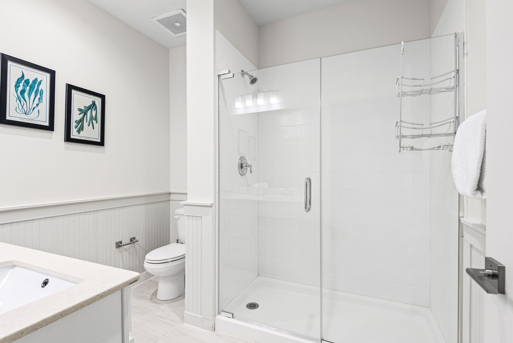 A modern bathroom with a glass-enclosed shower, a toilet, and a sink.
