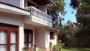 A two-story house with a balcony, a lawn, and potted plants.