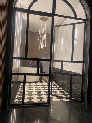 Eine Lobby mit Schachbrettmuster-Boden, einer Rezeption und einer Chandelüster.