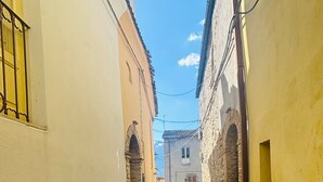 Un estrecho callejón empedrado, flanqueado por edificios con muros de piedra y arcos.