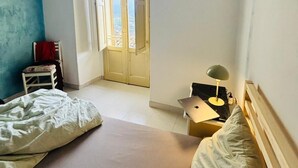 Un dormitorio con cama, escritorio, silla, lámpara y ventana con vistas.