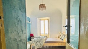 Un dormitorio con cama, ventana y lámpara colgante.