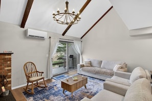 A living room with a sofa, a rocking chair, a coffee table, and a chandelier.