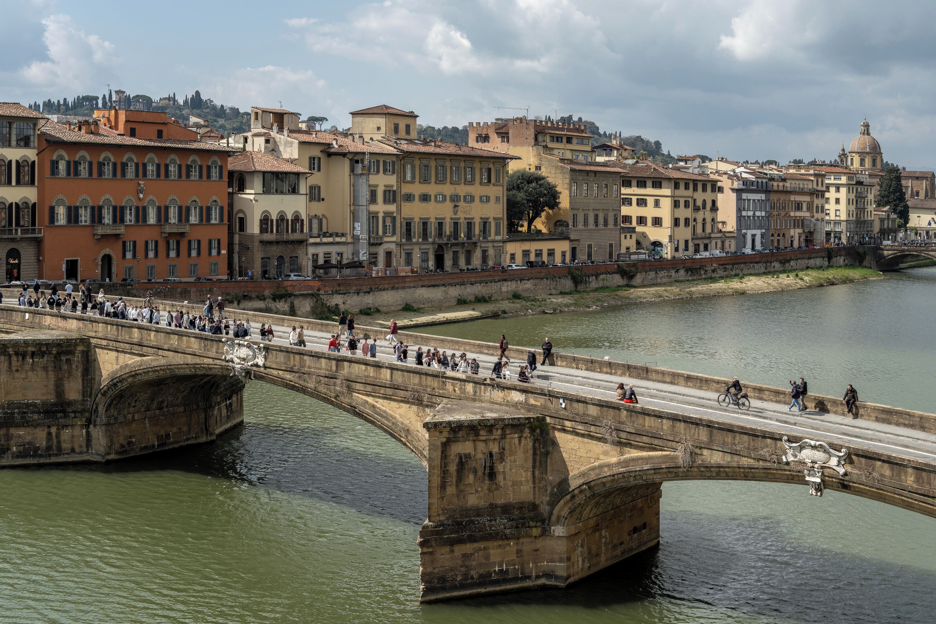 A stone bridge over a river with buildings on the opposite bank.