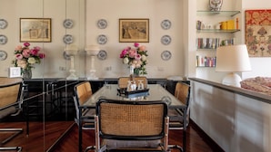 Un coin repas avec une table en verre, des chaises en osier et un vase rempli de fleurs.