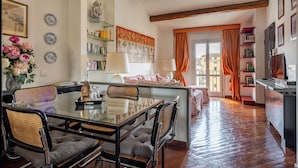 Un coin repas avec une table en verre, des chaises et une bibliothèque.