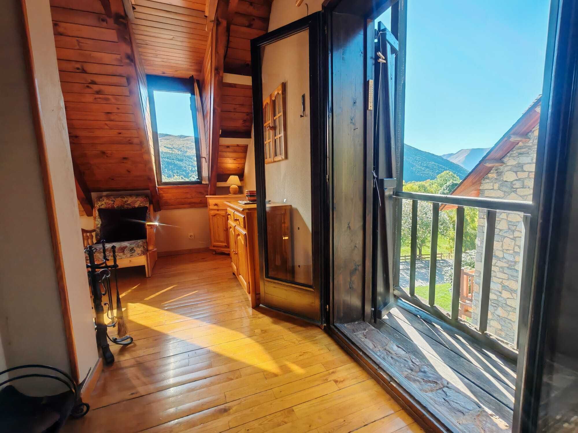 Ein Holzinnenraum mit Blick auf Berge vom Balkon aus.