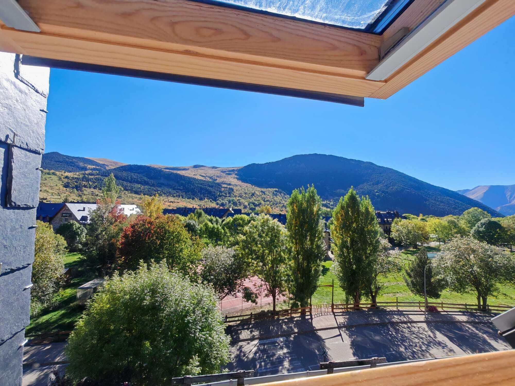 A view from a window overlooking a mountainous landscape with a clear sky.