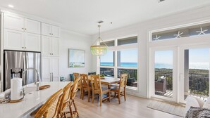 Eine moderne Küche mit weißen Schränken, einem Edelstahl-Kühlschrank und einem Essbereich mit Holztischen und -stühlen.