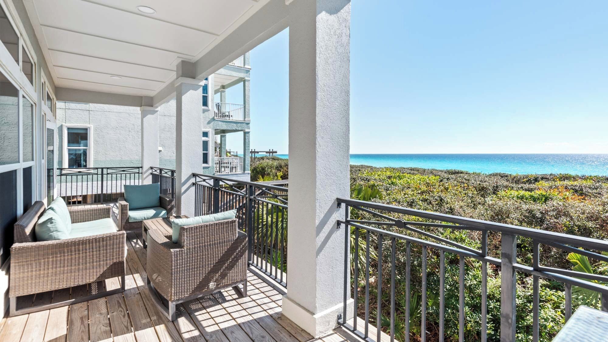 A covered balcony with wicker furniture and a view of the ocean.