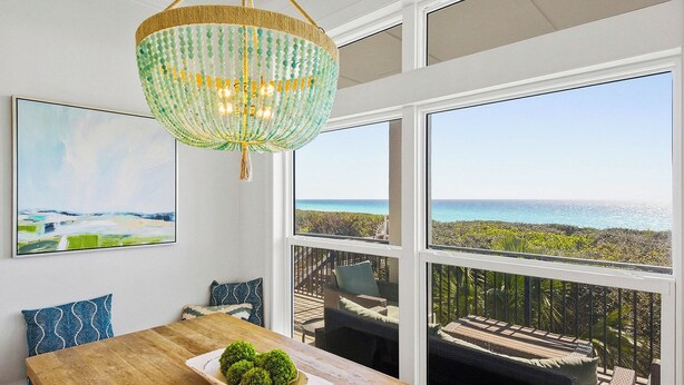 Ein Essbereich mit Blick auf das Meer, einer Kristallleuchtre und Kunstwerken an der Wand.