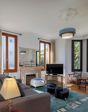 Un salon avec une cheminée, un téléviseur, un canapé et un coin repas comprenant une table et des chaises.