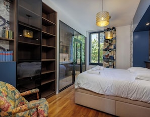 Une chambre à coucher avec un lit, une armoire, une chaise et une fenêtre avec des stores.