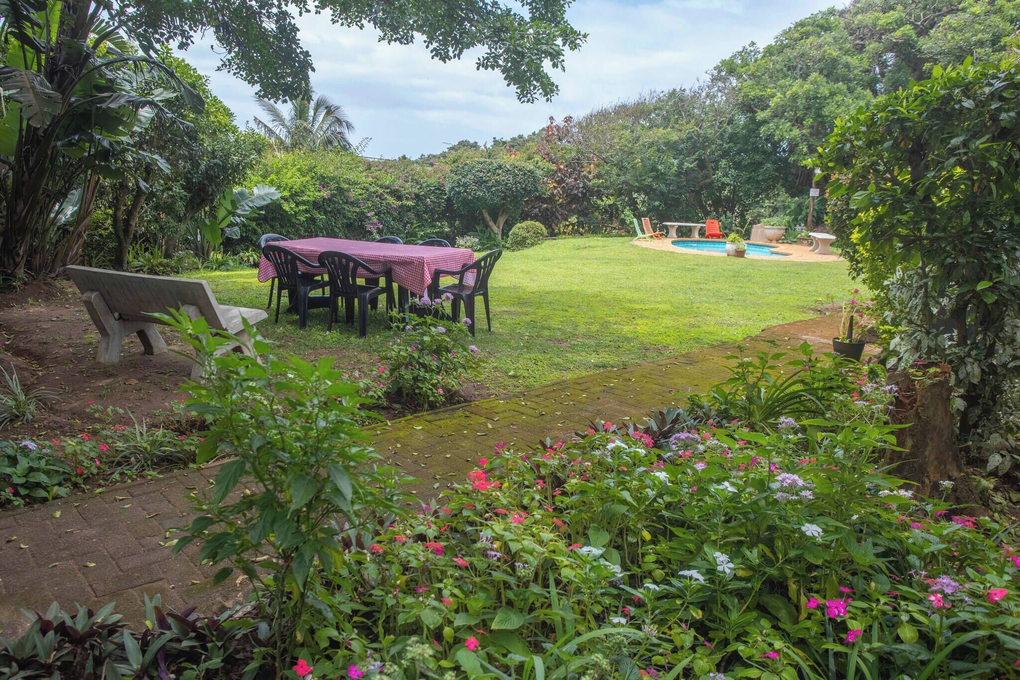 Un jardín con una mesa, sillas y un banco.