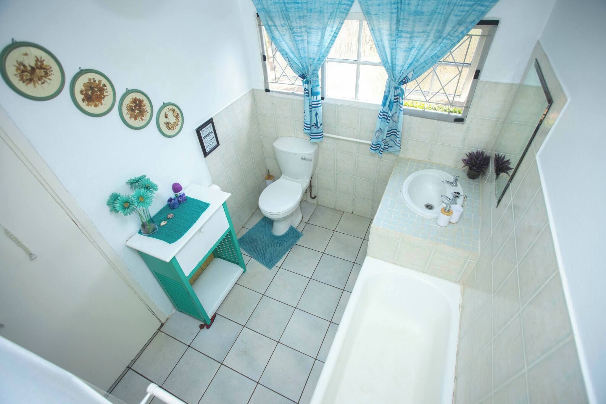 Ein Badezimmer mit Toilette, Waschbecken, Badewanne und einem Fenster mit Vorhängen.