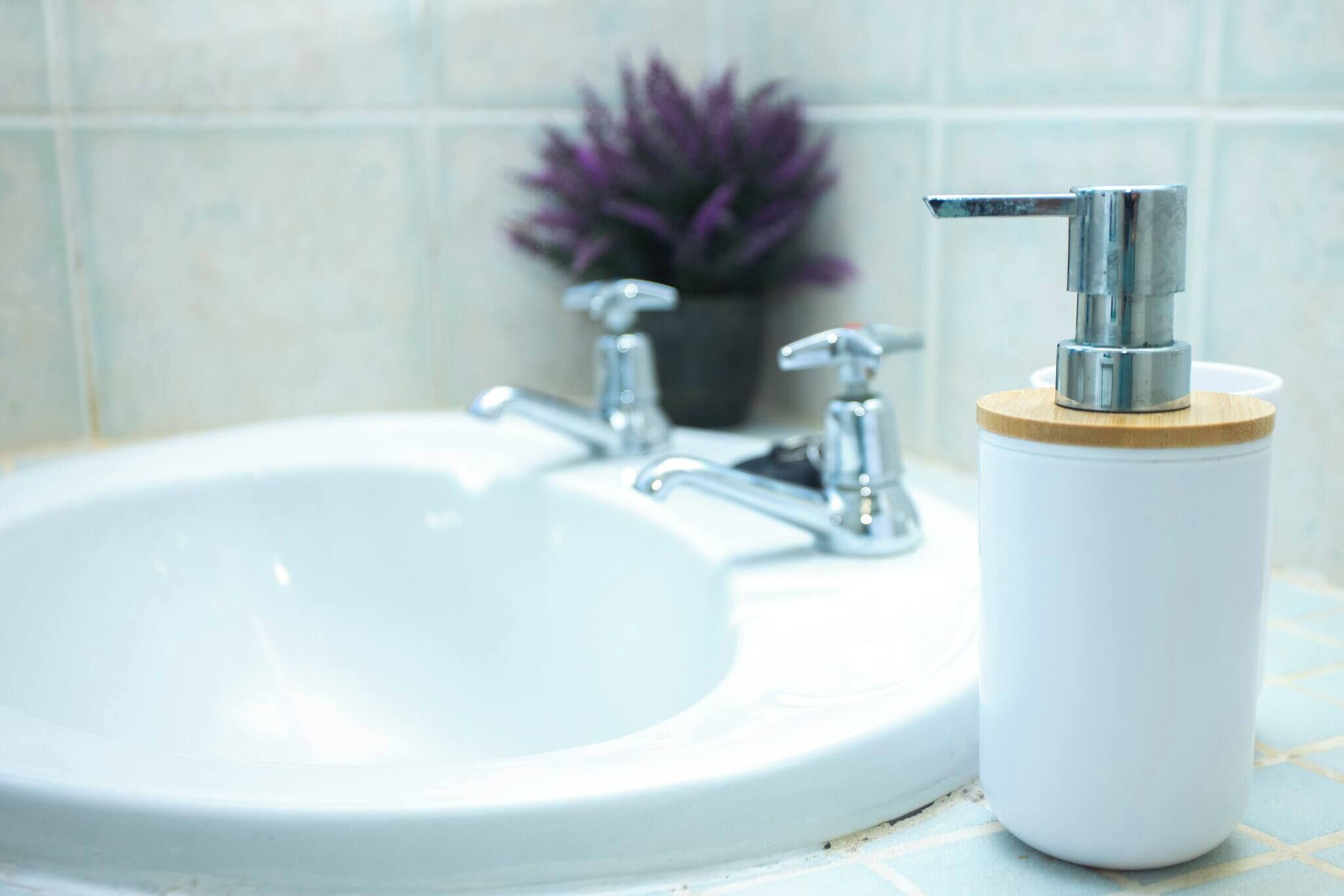 A bathroom sink with a faucet and a soap dispenser.
