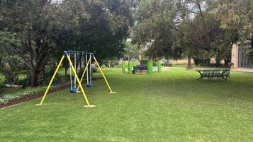 Un parque con un columpio, una mesa de picnic y un banco.