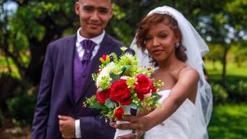A wedding couple holding a bouquet of red roses.