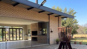 A modern house with a brick exterior, large windows, and a patio area with a circular brick fire pit. - Antelope Farm Events (Akasia)
