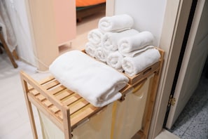 Un étagÚre en bois sur laquelle sont soigneusement pliées des serviettes blanches.