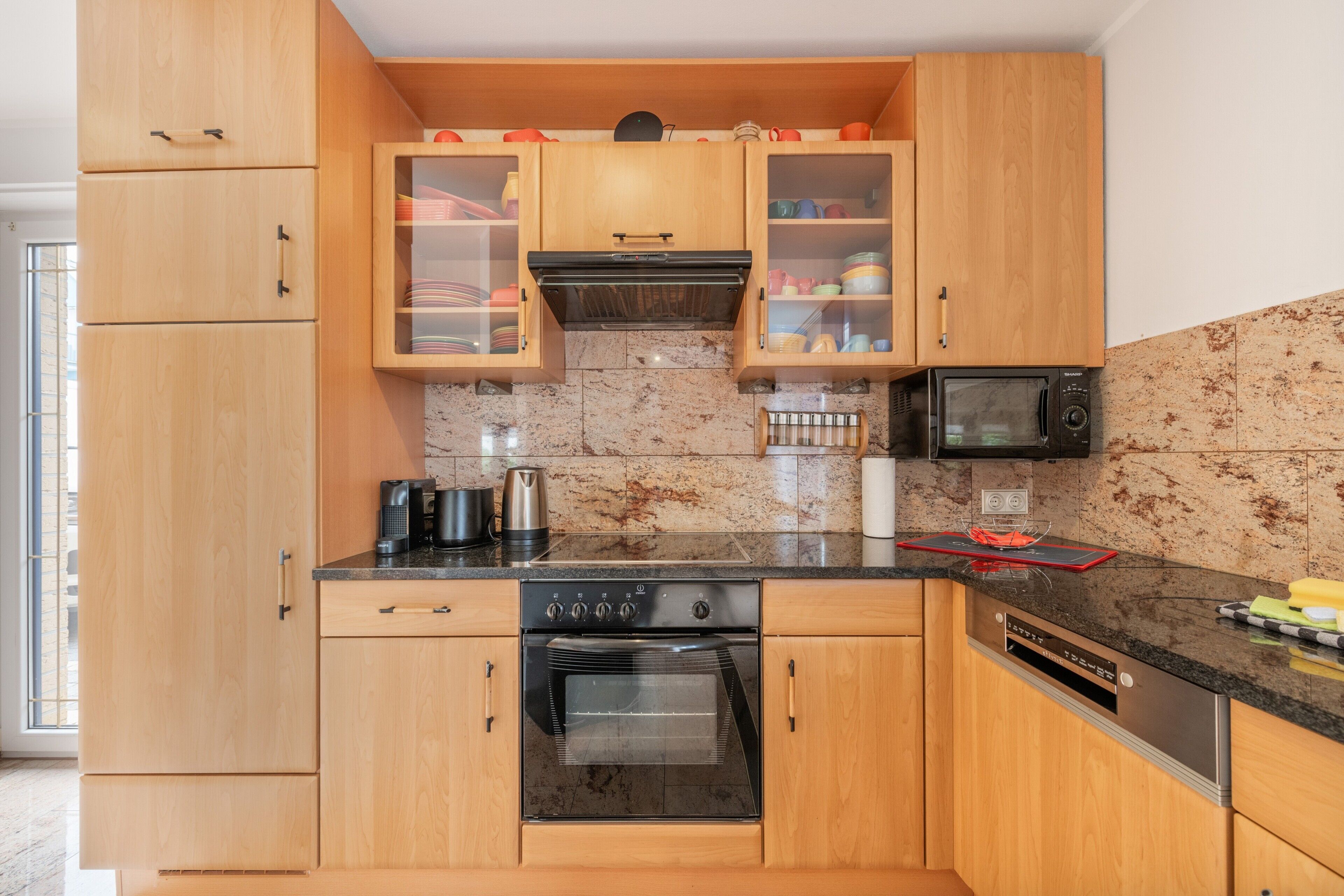 Eine Küche mit Holzausstattung, einer Mikrowelle, einem Backofen und einer Kaffeemaschine.