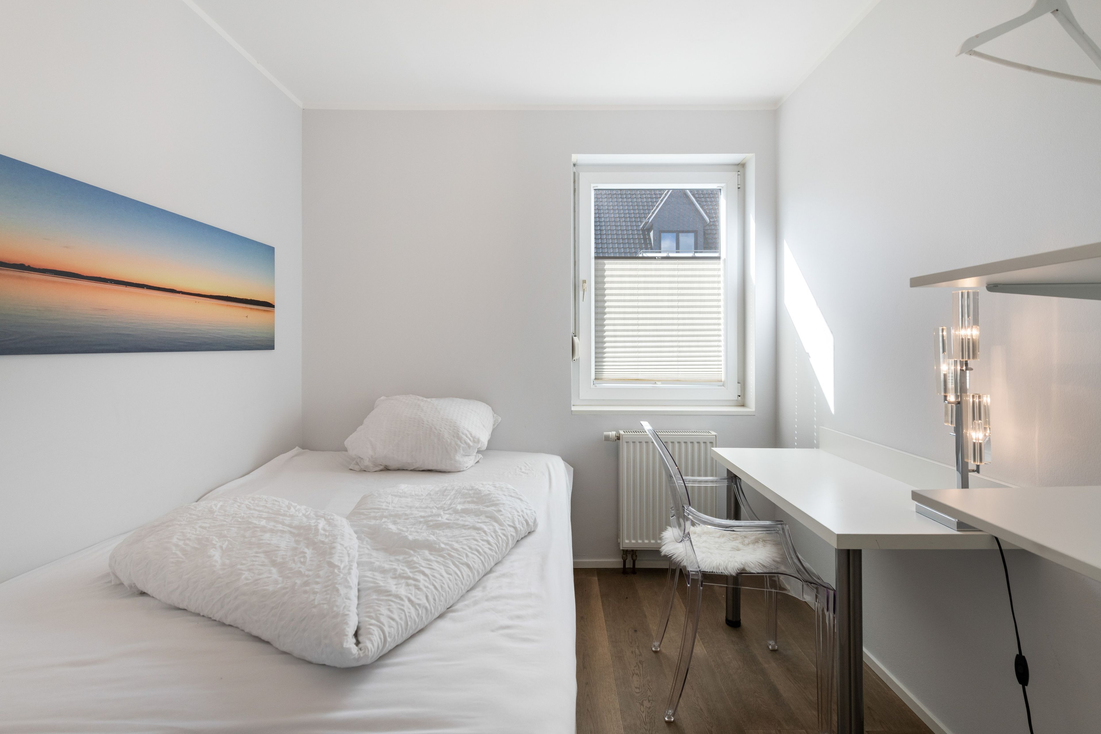 Quarto com cama, escrivaninha e radiador.